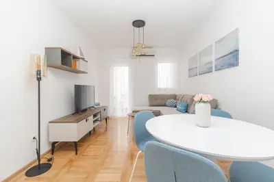 a living room with a white table and blue chairs at New Renovated Warm Cozy Fully Equipped One Bedroom Apartment in Budva, Free Parking, Ideal for Long Stays in Budva