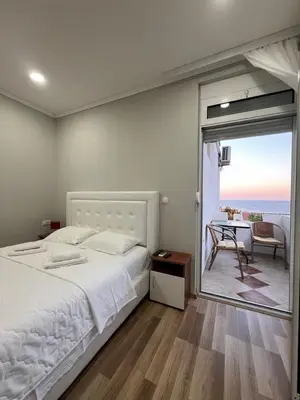 a bedroom with a bed and a balcony with a table at L&I Villa in Ulcinj