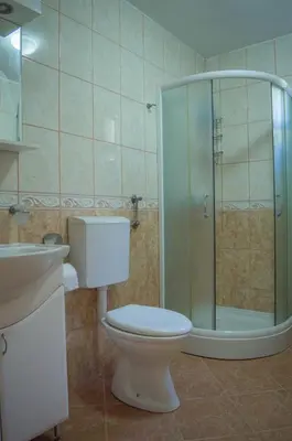a bathroom with a toilet and a glass shower at Apartments Macaso in Bar