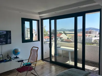 a living room with a table and chairs and windows at Apartman Andrea in Bar