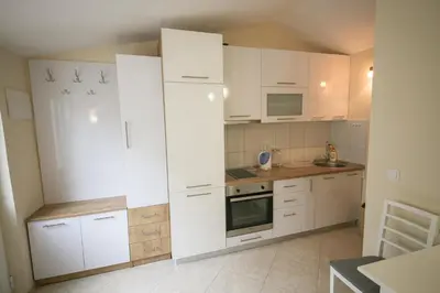 a white kitchen with white cabinets and a stove at Goga Apartment in Kotor