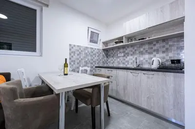 a kitchen with a table with a bottle of wine at Petrovac Holiday Apartments 2 in Petrovac na Moru