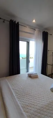 a bedroom with a large white bed with a window at Kahari Apartments in Ulcinj