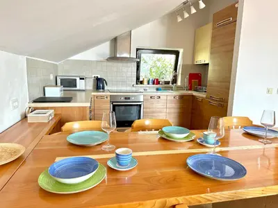 a kitchen with a wooden table with plates and wine glasses at PalmOliva in Rafailovici