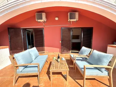 a patio with chairs and a table and a red wall at PalmOliva in Rafailovici
