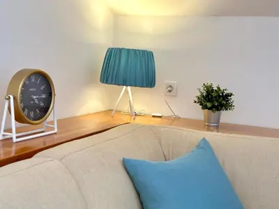 a living room with a couch and a clock on a table at PalmOliva in Rafailovici