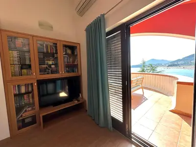 a living room with a tv and a sliding glass door at PalmOliva in Rafailovici