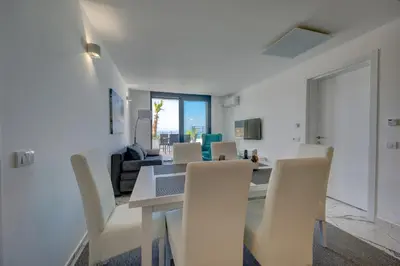 a dining room with a table and white chairs at Sea Salt Apartment in Kruče