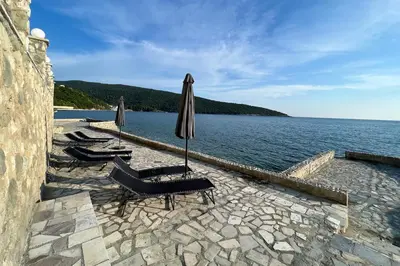 a group of chairs and umbrellas next to the water at Sea Breeze Apartment in Kruče