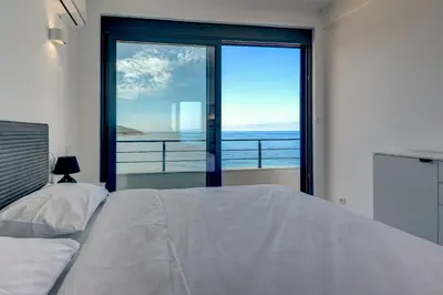 a bedroom with a bed and a view of the ocean at Sea Breeze Apartment in Kruče