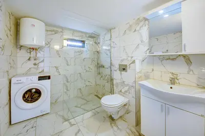 a bathroom with a toilet and a washer and dryer at Sea Breeze Apartment in Kruče