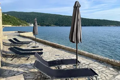a group of chairs and umbrellas next to a lake at Sea Wave Apartment in Kruče