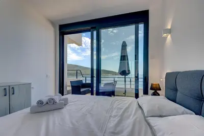 a bedroom with a bed with a view of the ocean at Sea Wave Apartment in Kruče