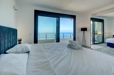 a bedroom with a large white bed with large windows at Sea Wave Apartment in Kruče
