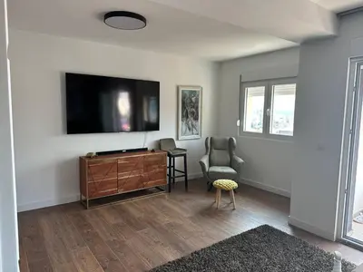 a living room with a tv and a chair at Penthouse NIKOLA in Budva