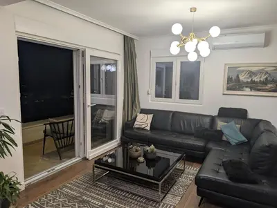 a living room with a black leather couch and a table at Penthouse NIKOLA in Budva