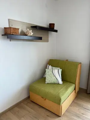 a green chair sitting in a corner of a room at Apartments Andrović in Ulcinj