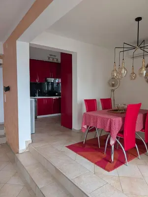 a dining room with a table and red chairs at Vila Anja in Dobra Voda