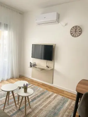 a white living room with two tables and a flat screen tv at Le Vacanze in Ulcinj