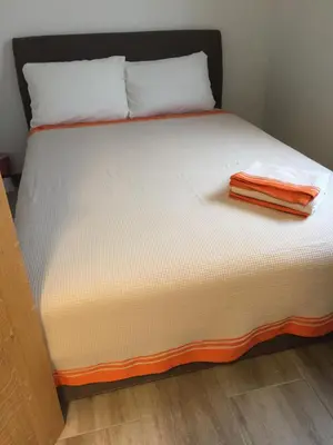 a bed with an orange towel on top of it at Monimont in Golubovci