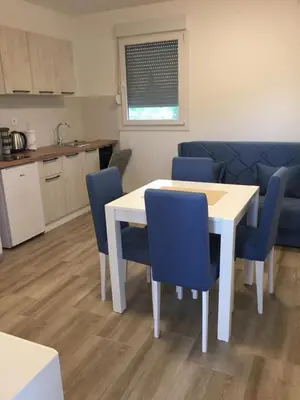 a kitchen and dining room with a white table and blue chairs at Monimont in Golubovci