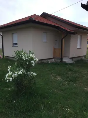 a small white house with a grassy yard at Monimont in Golubovci