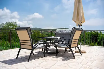 two chairs and a table and an umbrella on a patio at Villa Jovana in Zagora