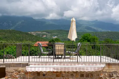 a table and chairs and an umbrella on a balcony at Villa Jovana in Zagora