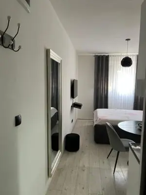 a room with a bed and a table and a mirror at Lux Cotton in Podgorica