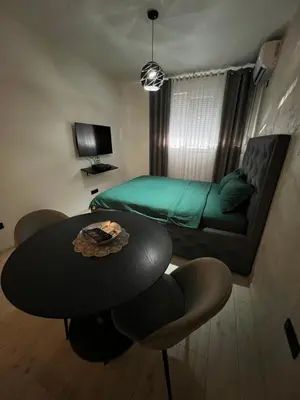a small room with a table and a bed at Lux Cotton in Podgorica