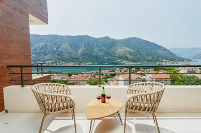 two chairs and a table with a bottle of wine on a balcony at Horizon Bay with Sea View in Kotor