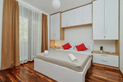 a bedroom with a bed with white cabinets and red pillows at Horizon Bay with Sea View in Kotor