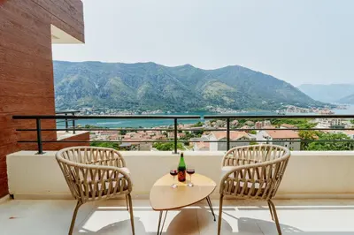 two chairs and a table with a bottle of wine on a balcony at Horizon Bay with Sea View in Kotor