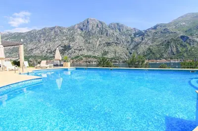 a large swimming pool with mountains in the background at Sea view and pool! Brend new! Vista in Kotor