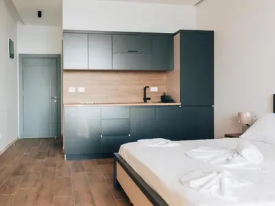 a bedroom with a bed with white sheets and a kitchen at Hayal Boutique Hotel in Bar
