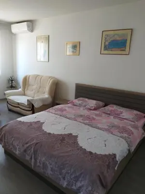 a bedroom with a large bed and a chair at Apartment in Podgorica - Montenegro in Konik