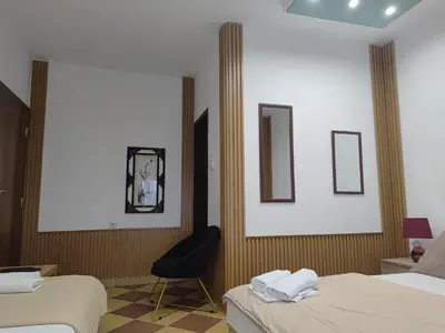 a hotel room with two beds and a chair at Becic Apartments in Ulcinj