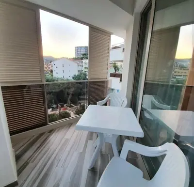 a white table and white chairs on a balcony at Sirius apartaments in Rafailovici