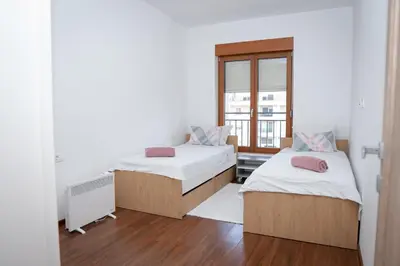 two beds in a room with a window at Apartment Minna Master Quart in Podgorica