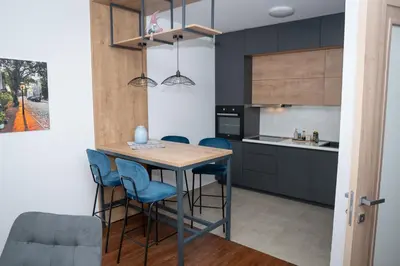 a kitchen with a wooden table and blue chairs at Apartment Minna Master Quart in Podgorica