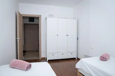 a white bedroom with two beds and a closet at Apartment Minna Master Quart in Podgorica