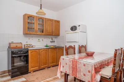 a kitchen with a table and a white refrigerator at Apartman Glendza in Ulcinj