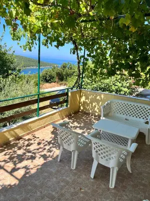 a picnic table and chairs on a patio overlooking the ocean at Apartman Perić in Bigovo