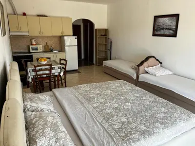 a living room with two beds and a kitchen with a table at Apartman Perić in Bigovo
