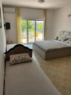 a bedroom with two beds and a balcony at Apartman Perić in Bigovo