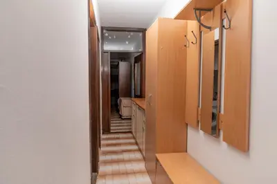 a hallway leading to a bathroom with wooden cabinets at Glendza Apartman in Ulcinj