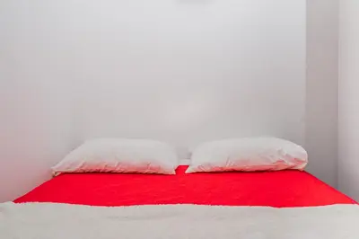 two pillows on a bed with a red and white blanket at Glendza Apartman in Ulcinj