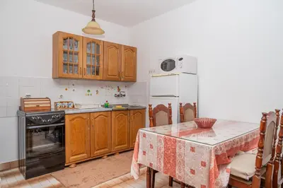 a kitchen with a table and a white refrigerator at Glendza Apartman in Ulcinj