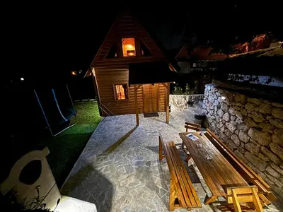 a wooden cabin with a bench and a stone wall at Brvnara RIĆKI in Cetinje