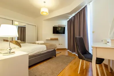 a hotel room with a bed and a desk and a chair at Apartments RONDO in Ulcinj